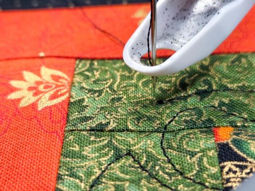 A sewing machine needle on green fabric