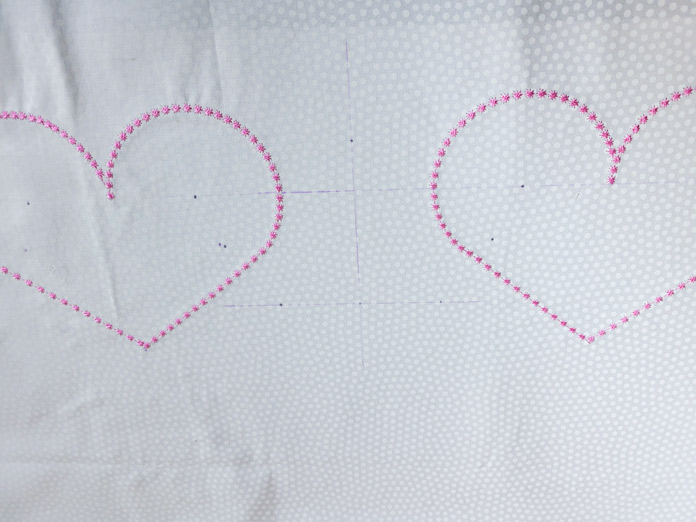 Two pink hearts on white fabric