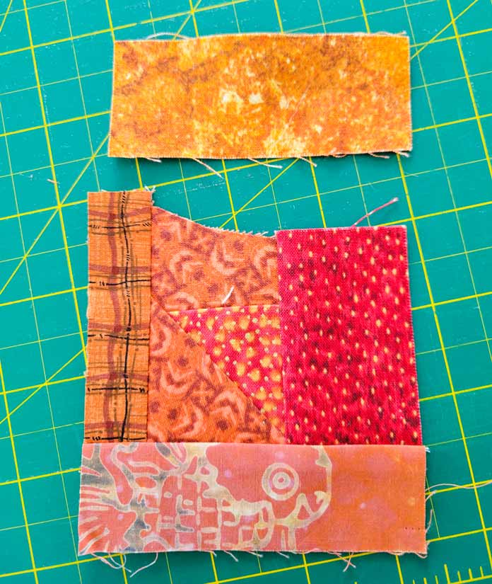 Scraps of orange fabric sewn together and sitting on a green cutting mat; Husqvarna Viking DESIGNER EPIC 2