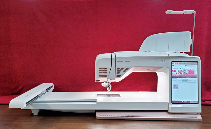 A burgundy and white sewing machine with an extension table; Husqvarna Viking DESIGNER EPIC 2