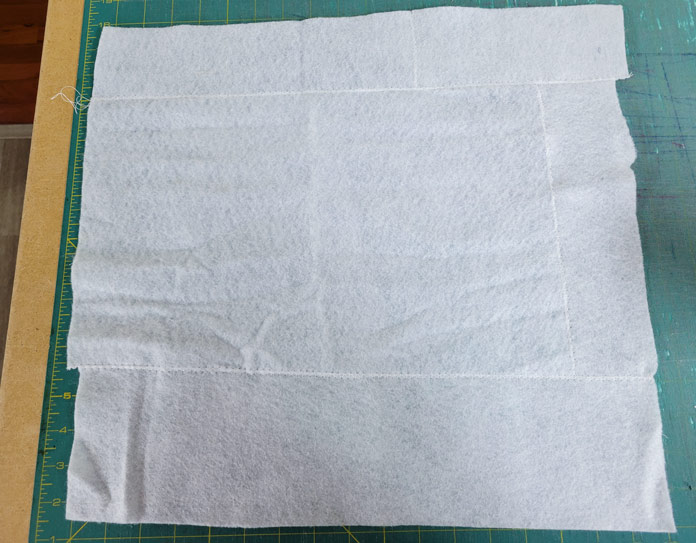A white square of fabric on a green cutting mat; Husqvarna VIKING ONXY 25
