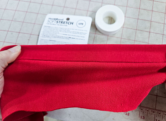 Stretching a red fabric; Learn how to use HeatnBond SOFTSTRETCH fusible web on knits, denim, fleece, and more