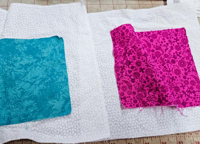 A teal square on white fabric and pink fabric on a white background; HeatnBond, fusible web, sewing, applique, quilting, hemming, fabric adhesive, SoftStretch, Lite, Featherlite, Ultra, sewing tips, crafting, fabric experiments