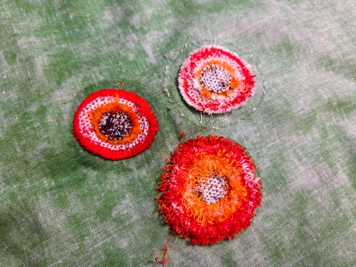 The wrong side of three machine-embroidered flowers