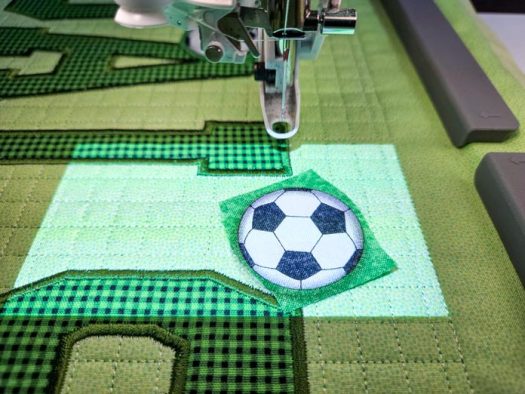 Soccer ball fabric on green fabric in a machine embroidery hoop