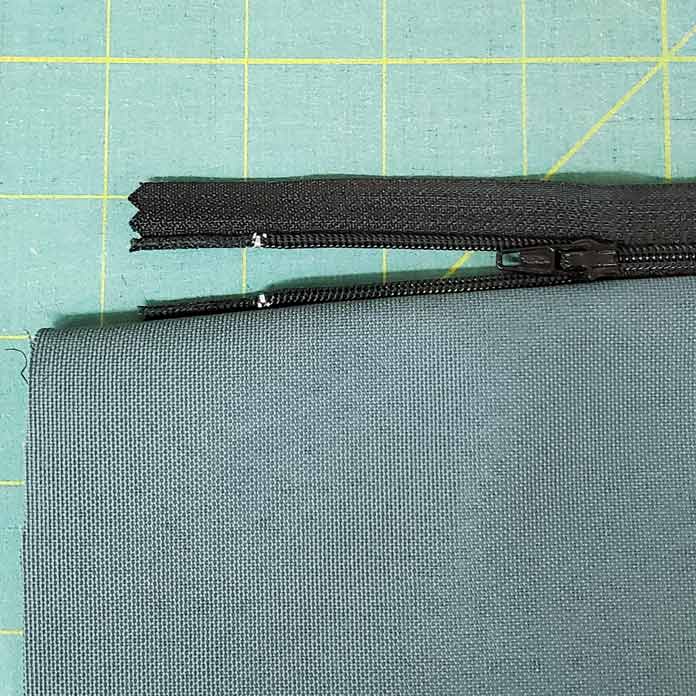 A black zipper is sticking out from a piece of green fabric. Husqvarna Viking Designer Sapphire 85, Inspira EZ Snip Curved Scissors