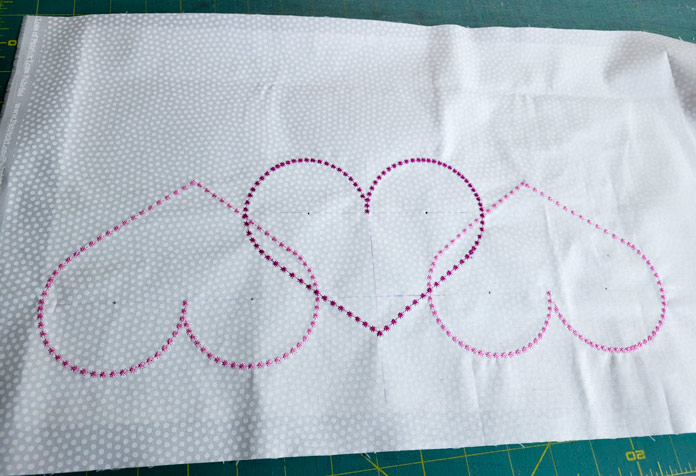 Three pink hearts on white fabric