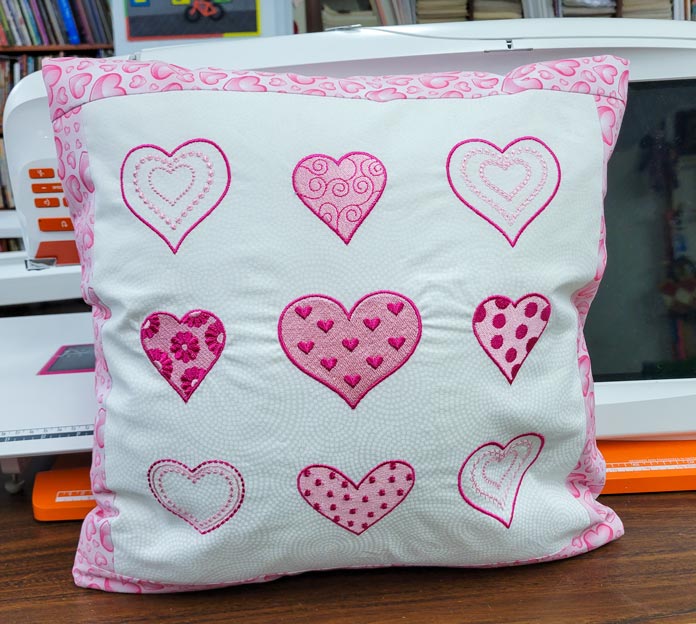 A pink and white cushion cover with hearts; Husqvarna Viking DESIGNER EPIC 2