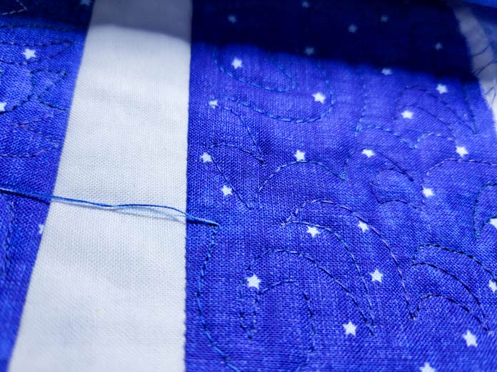 Stitching with blue thread on blue and white fabric