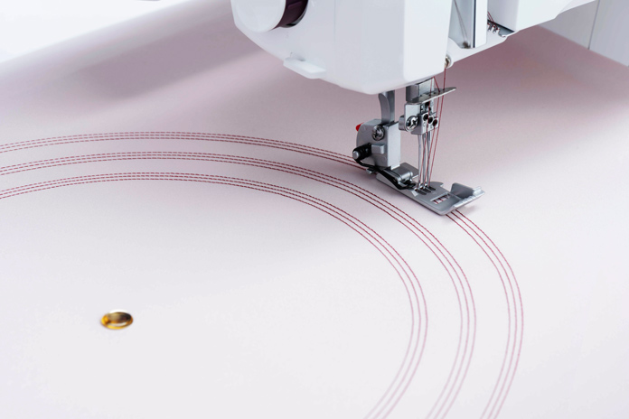 A push pin and lines of stitching on pink fabric; Husqvarna Viking Amber Air S600