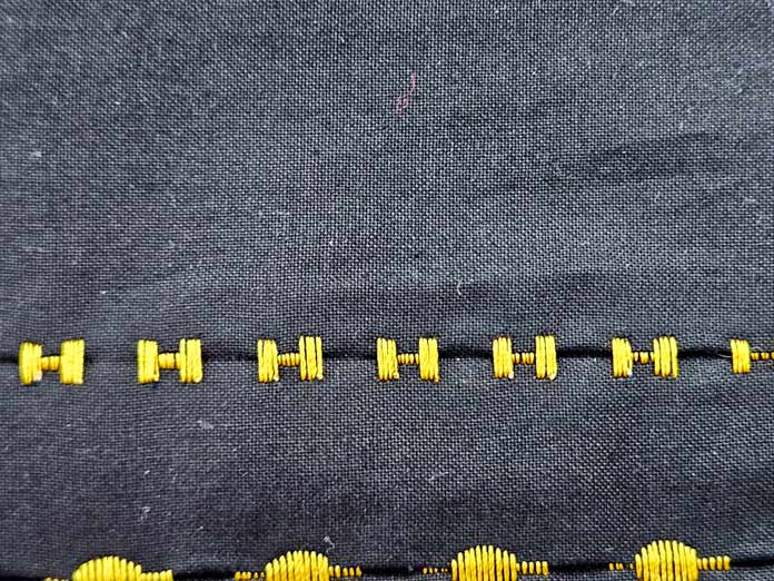 A line of yellow satin stitches on black fabric; Husqvarna VIKING DESIGNER EPIC 3