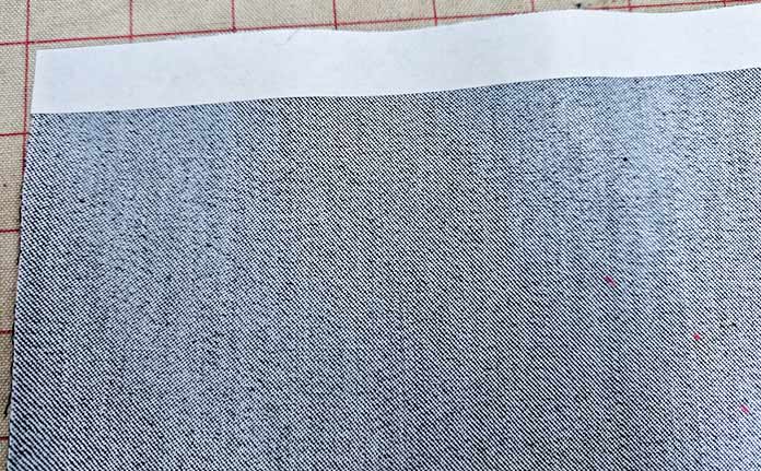 A strip of white along denim fabric; Learn how to use HeatnBond SOFTSTRETCH fusible web on knits, denim, fleece, and more