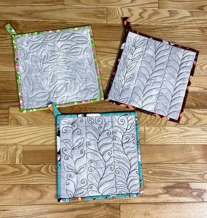 3 potholders made with quilted samples showing leaf, plume and swirl free motion quilting designs; Fabric Creations