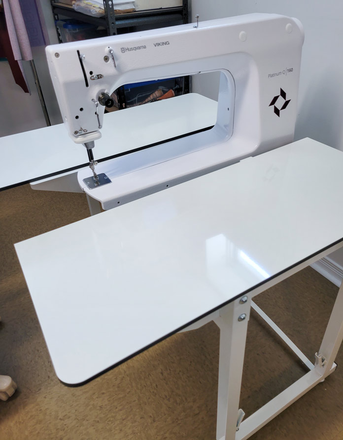 A stationary quilting machine on a white table; Husqvarna Viking PLATINUM™ Q160