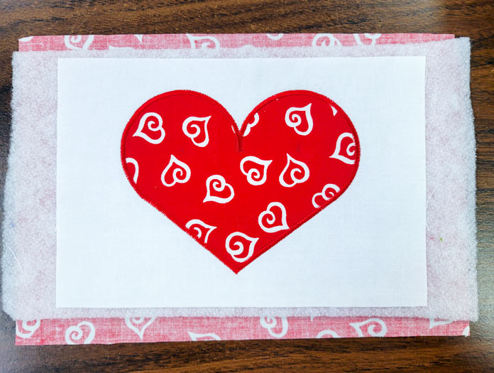 A red applique heart on white fabric