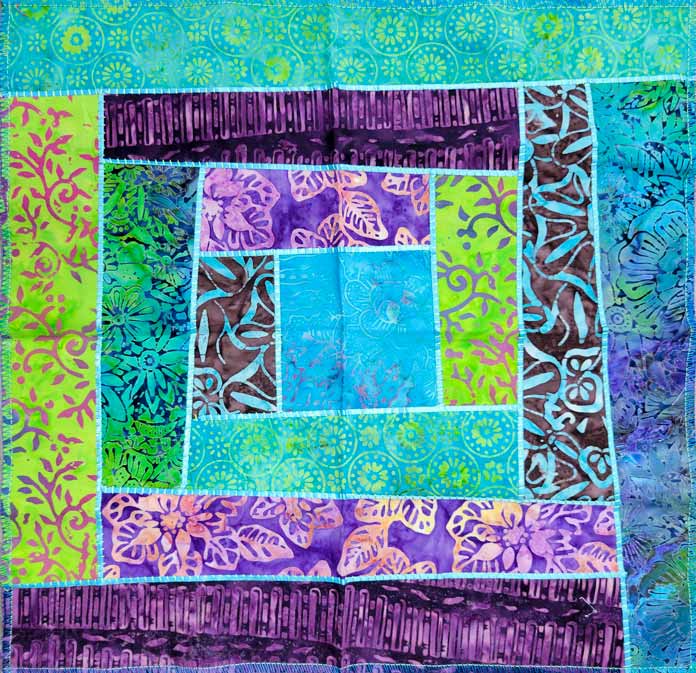 A multi-color quilt block with teal ribbon