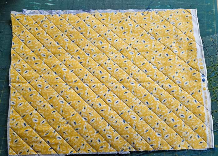 Blue lines of stitching on yellow fabric
