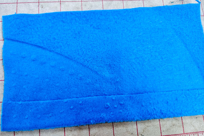 A blue piece of fleece with a hem; Learn how to use HeatnBond SOFTSTRETCH fusible web on knits, denim, fleece, and more