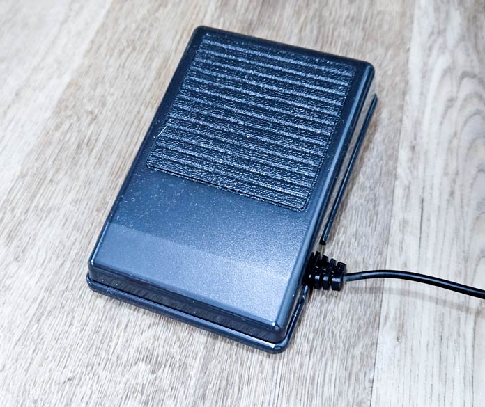 A black foot pedal for a sewing machine