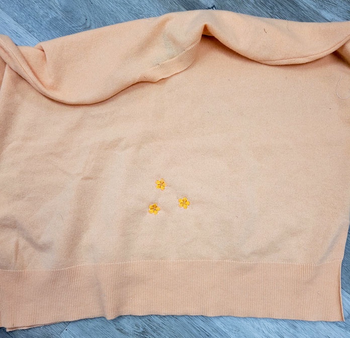 The cashmere sweater after the repair using machine embroidered flowers