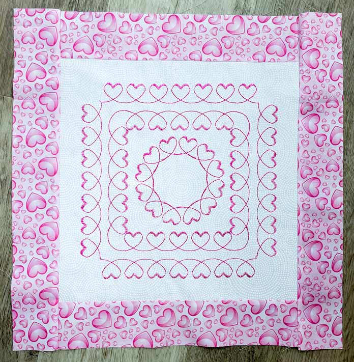 Two squares and a circle of pink hearts on white fabric with a pink fabric border
