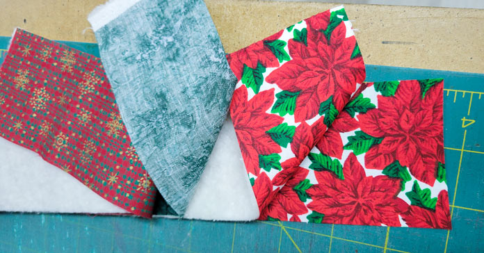 Layers of green and red fabric with white batting