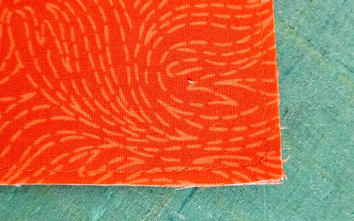 A rectangle of orange fabric on a green cutting mat; assembling the project bag the Husqvarna VIKING ONYX 25