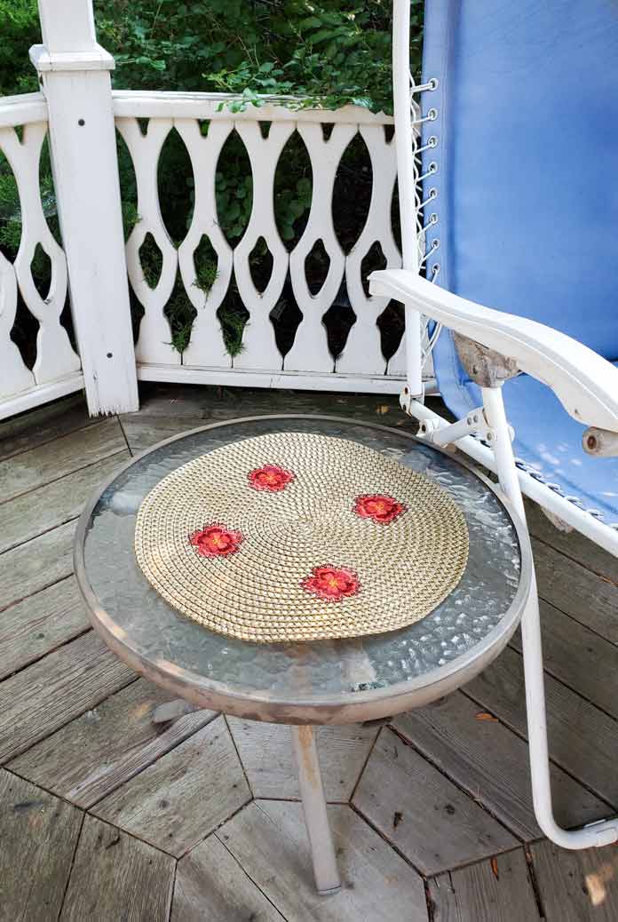 A machine embroidered rattan table topper on a round table in a gazebo