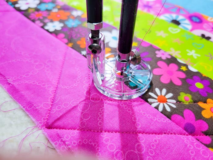 A plastic round foot on pink fabric on a stationary quilting machine; Husqvarna Viking PLATINUM™ Q160, Husqvarna Viking Echo Feet Set
