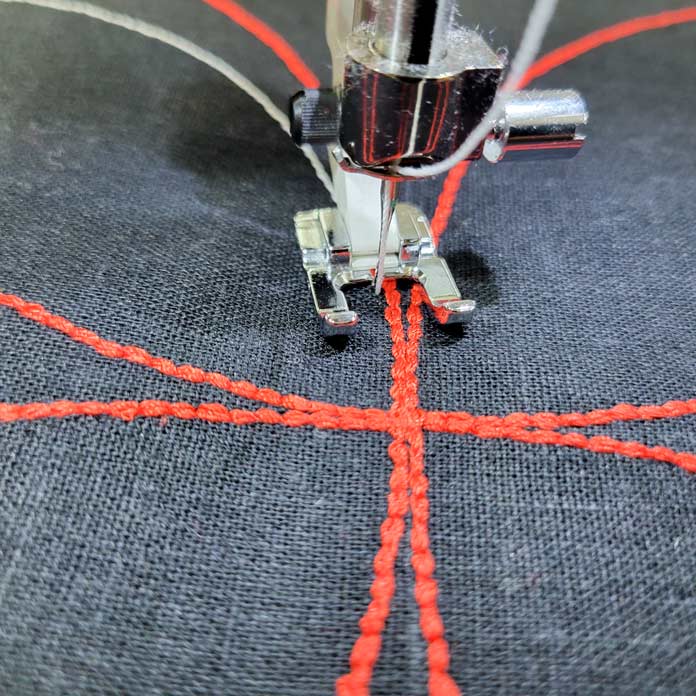 Curved lines of red stitching on black fabric; Husqvarna Viking Tribute 150C, Gütermann topstitching threads