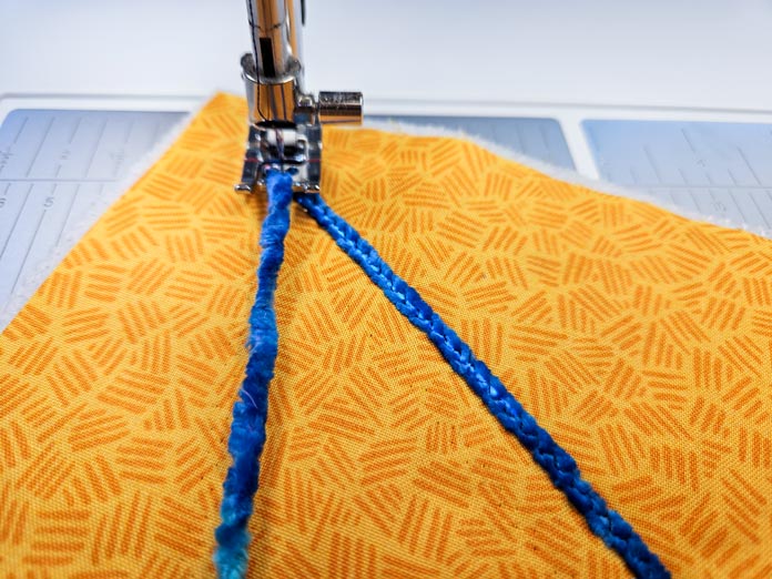 Blue lines of yarn on yellow fabric