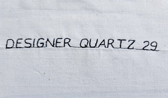 Black letters on beige fabric stitched out on the Husqvarna VIKING Designer Quartz 29