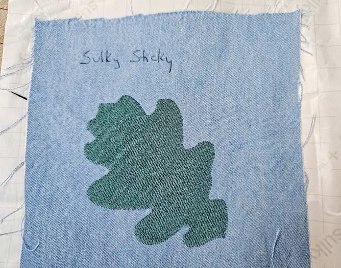 A green leave stitched on blue fabric