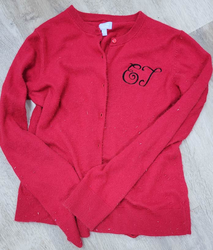 A red sweater with a two-letter monogram in black thread