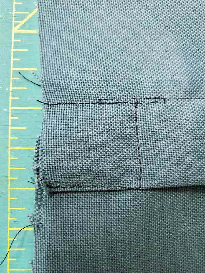 Black thread stitched on green fabric at the end of a zipper closure. Husqvarna Viking Designer Sapphire 85, Inspira EZ Snip Curved Scissors