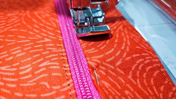 A pink zipper and orange fabric with a metal presser foot; making a project bag on the Husqvarna VIKING ONYX 25