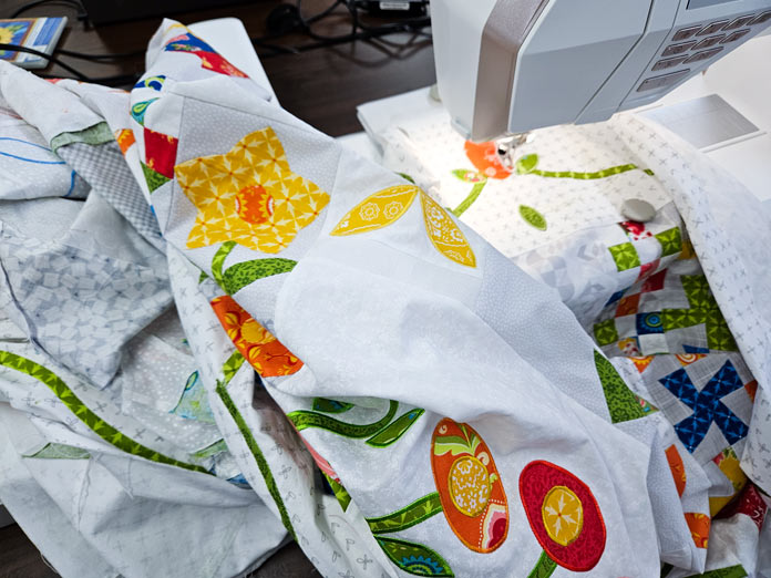 A colorful quilt on a white background under the head of an embroidery machine