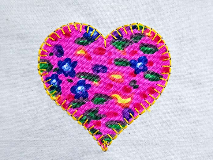 A pink fabric heart on a beige background with yellow stitching; Husqvarna VIKING Designer Quartz 29, mySewnet Machine Embroidery Software, Husqvarna VIKING Tear-a-Way Light Stabilizer 15 Inches x 25 Yards