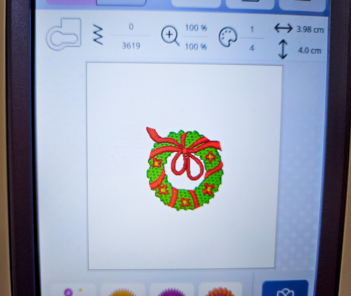 A green and red Christmas wreath on the screen of a computerized sewing and embroidery machine; Husqvarna VIKING Designer Quartz 29, mySewnet Machine Embroidery Software, mySewnet Library, Husqvarna VIKING Tear-a-Way Light Stabilizer 15 Inches x 25 Yards