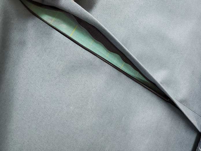 A partially open black zipper on the back of a green cushion. Husqvarna Viking Designer Sapphire 85, Inspira EZ Snip Curved Scissors