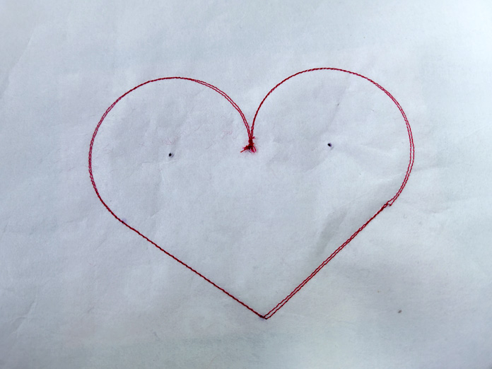 Two lines of red stitches in the shape of a heart on white