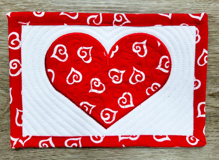 A red heart on white fabric with a red border
