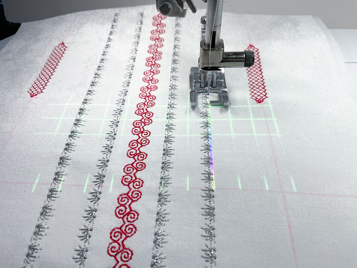 5 rows of decorative stitching in black thread and red thread sewn on white fabric using grid lines from the projector on the PFAFF creative icon 2.