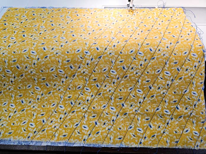 A yellow fabric with blue lines of stitching