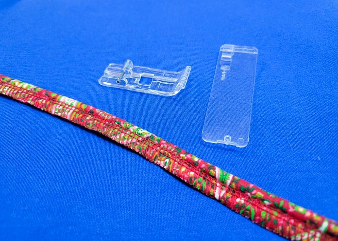 A red and green piece of piping with a clear plastic presser foot