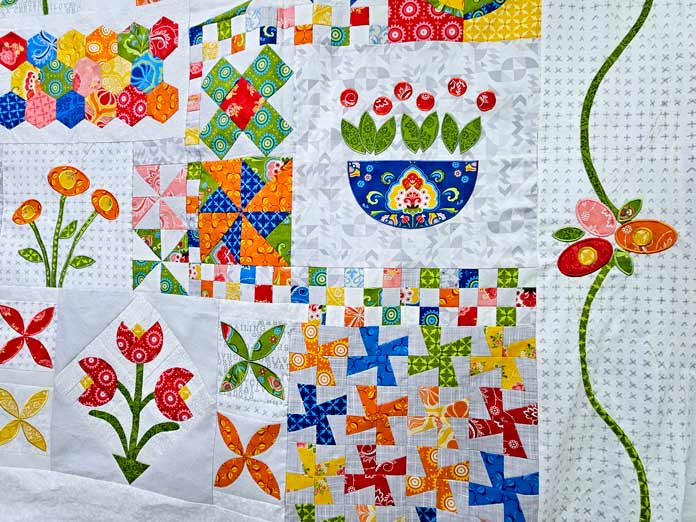 A colorful quilt with a white border and a green vine