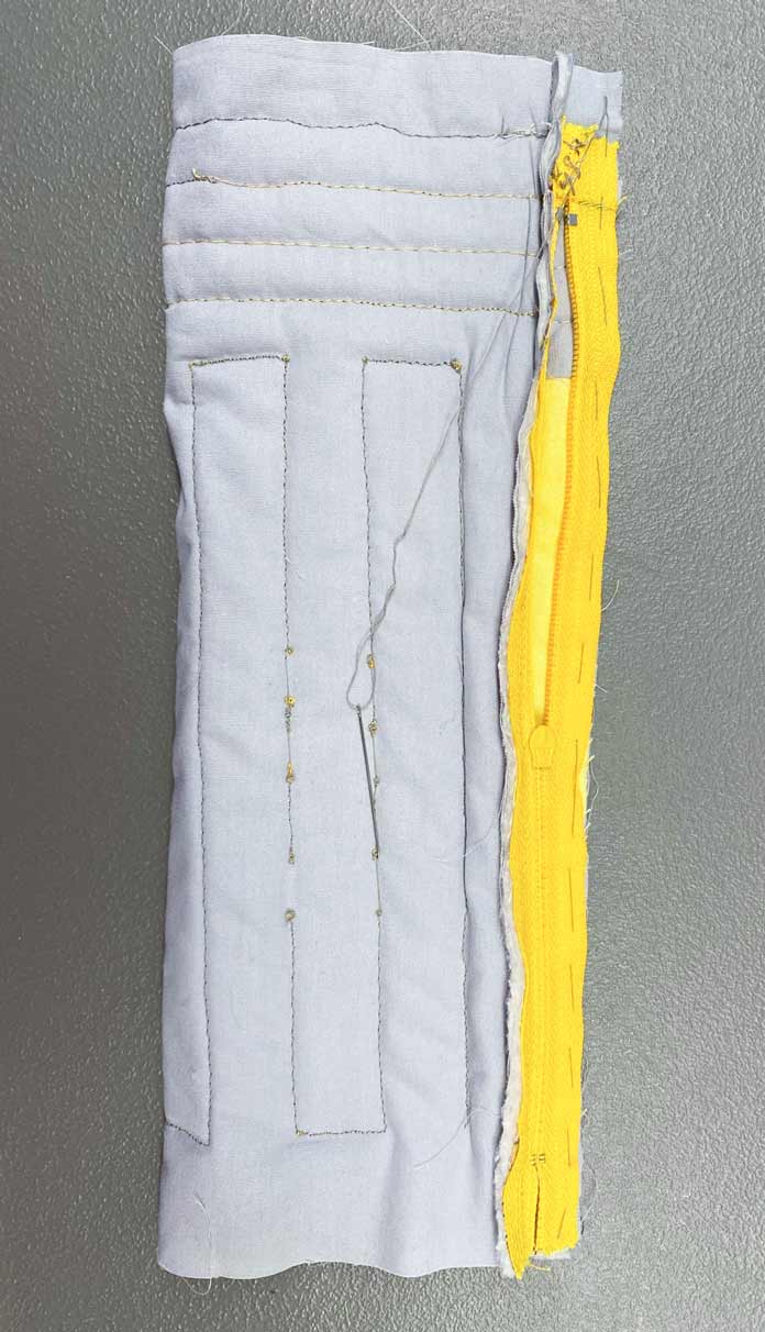 The unfinished quilted pencil case rolled up to the yellow zipper and sewn with a needle and thread; COSTUMAKERS General Purpose Closed End Zipper