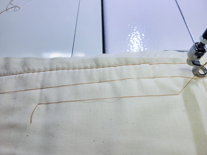 Long basting stitches in brown thread on cream fabric; Husqvarna Viking PLATINUM™ Q160