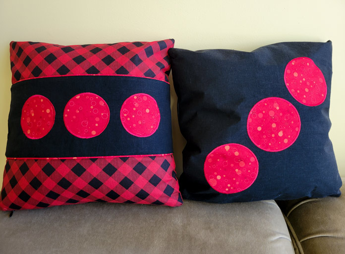 Two red and black appliqued cushion covers