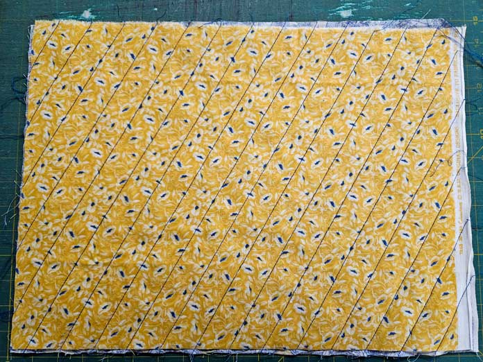 A yellow fabric with blue lines of stitching